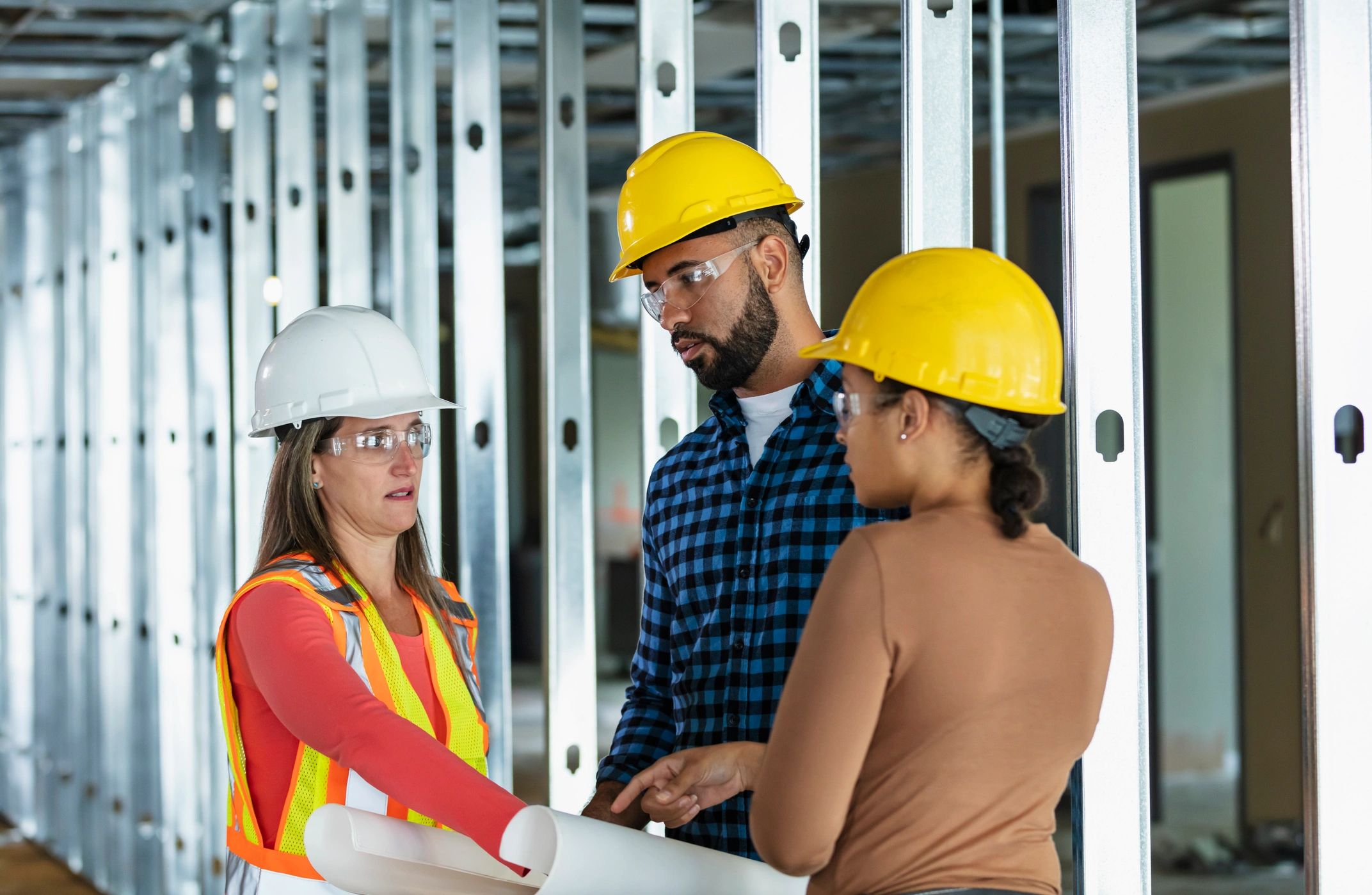 Three construction workers at job site with blueprints