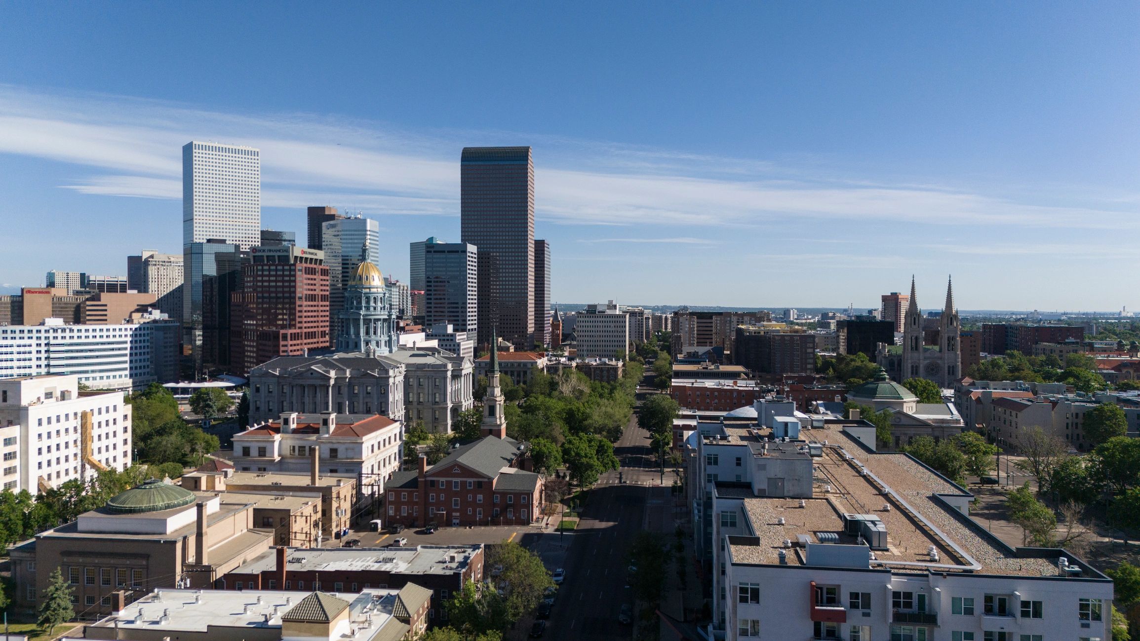 Urban skyline featuring Colorado State Capitol building and surrounding downtown district on sunny summer morning in Denver, CO.