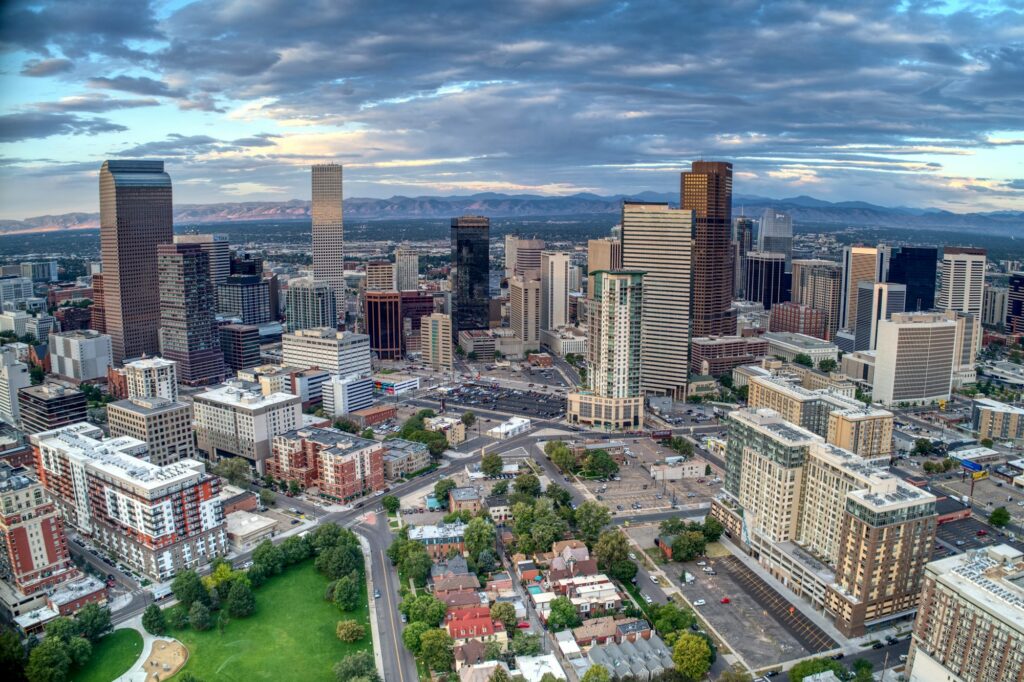 Downtown Denver office towers at daybreak with the Rocky Mountains behind